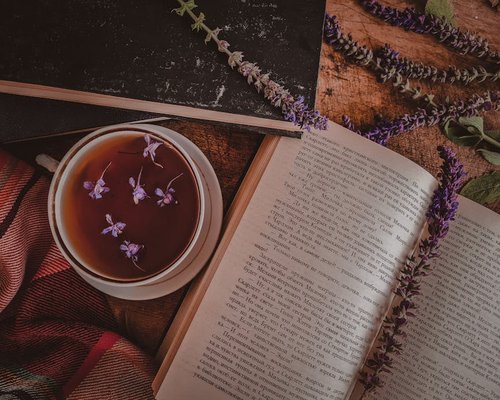 Close up of a cup of tea and a book on a wooden table